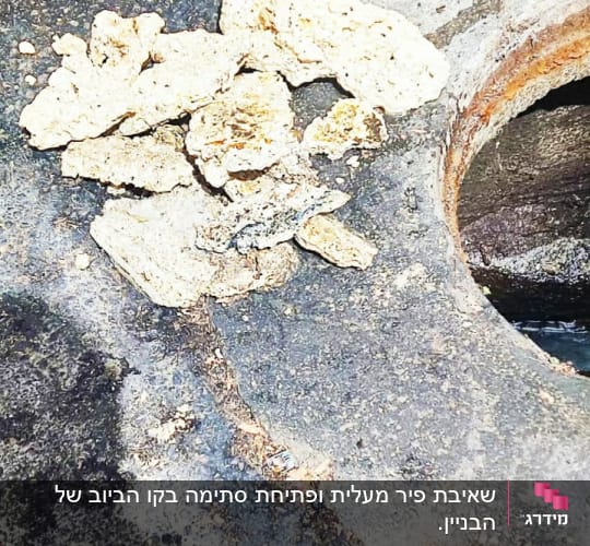 פתח ביוב עם מכסה פתוח וכלי עבודה על הקרקע